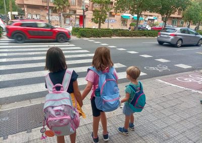 Infancias esperando en la acera para cruzar una calle
